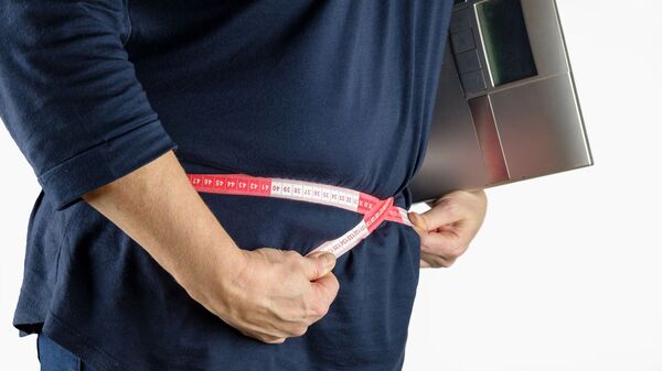 Una persona mide la circunferencia de su cintura con una cinta métrica - Sputnik Mundo