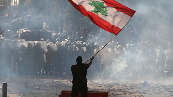 Un manifestante sostiene la bandera del Líbano durante las multitudinarias protestas contra la gestión del Gobierno tras la explosión en el puerto de Beirut, el 8 de agosto de 2020 - Sputnik Mundo