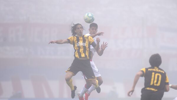 Futbolistas de Peñarol y Nacional disputan el balón en el clásico del fútbol uruguayo en medio de una intensa niebla - Sputnik Mundo