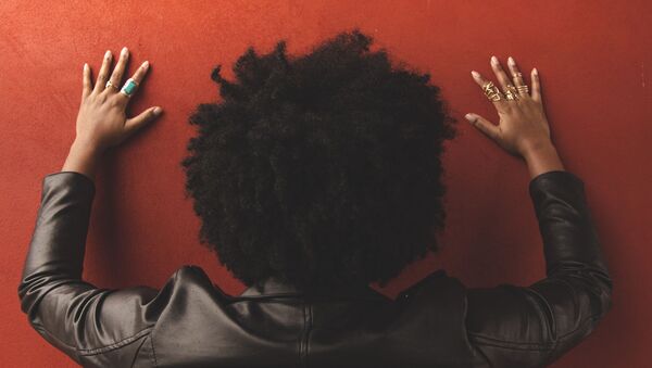 Persona con pelo afro apoyada contra una pared - Sputnik Mundo