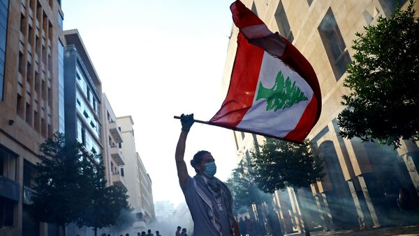 Un hombre con la bandera del Líbano durante las protestas en Beirut - Sputnik Mundo