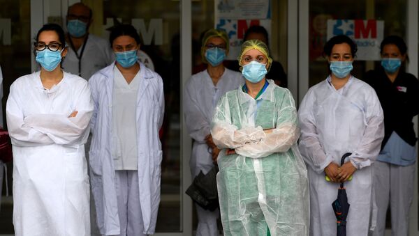 Los trabajadores sanitarios guardan un minuto de silencio para rendir homenaje a sus compañeros caídos frente al Hospital Gregorio Marañón - Sputnik Mundo
