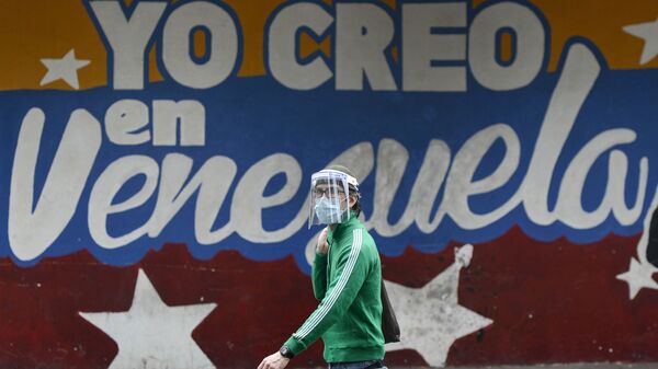 Un hombre pasa al lado de un mural en Caracas que dice yo creo en Venezuela - Sputnik Mundo