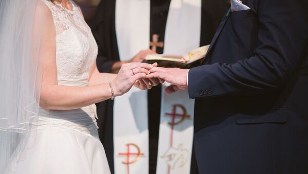Una mujer pone un anillo de bodas en el dedo de su marido (archivo) - Sputnik Mundo