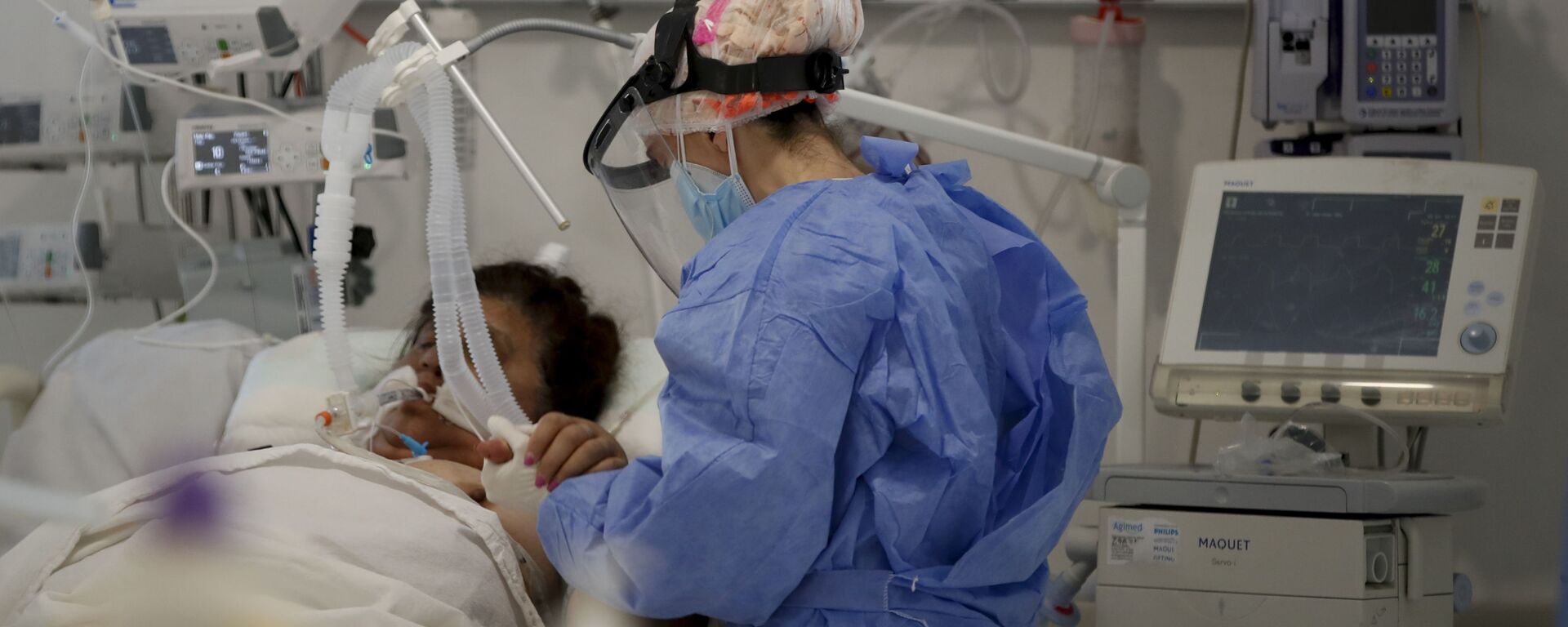 Una trabajadora de la salud atiende a un paciente en una unidad de cuidados intensivos designada para personas infectadas con coronavirus en un hospital en Buenos Aires (Argentina) - Sputnik Mundo, 1920, 14.04.2021