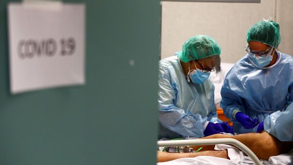 Trabajadores médicos atienden a un paciente infectado por COVID-19 en España - Sputnik Mundo