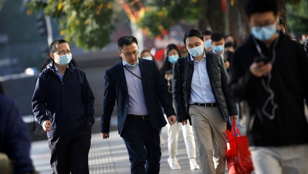 Una personas con mascarillas caminan por las calles de Pekín - Sputnik Mundo