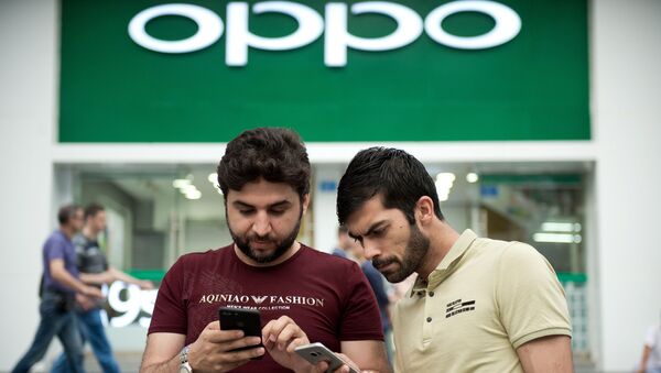 Dos personas con teléfonos inteligentes enfrente de la tiendad de Oppo en Shenzhen - Sputnik Mundo