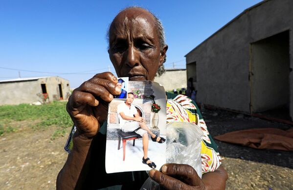 Эфиопская женщина показывает фото своих родственников - Sputnik Mundo
