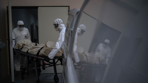 Trabajadores de una morgue recogen el cuerpo de una víctima de COVID-19 de un hogar de mayores en Barcelona, ​​España.  - Sputnik Mundo