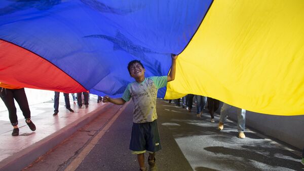 Un niño juega bajo una bandera venezolana - Sputnik Mundo