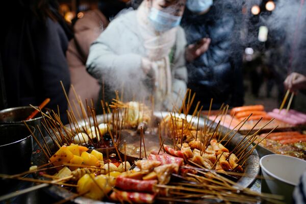 Muchos residentes de Wuhan continúan preocupados por no poder viajar durante las vacaciones de Año Nuevo como antes.En la foto: El comercio de alimentos en un mercado callejero de Wuhan. - Sputnik Mundo