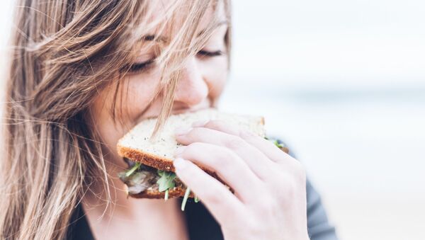 Una mujer comiendo un sándwich - Sputnik Mundo