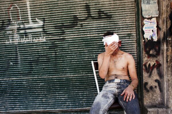 Un hombre herido por disparos cerca de una tienda cerrada en Alepo - 4 de septiembre de 2012. - Sputnik Mundo