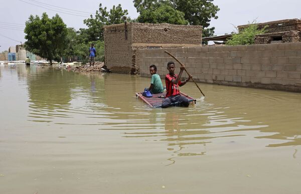 Las abundantes lluvias continuas en septiembre causaron inundaciones devastadoras en 16 provincias de Sudán. Se cobraron la vida de unas 100 personas y destruyeron más de 100.000 viviendas. En la foto: unos adolescentes navegan en una balsa por una calle inundada en la ciudad de Salmania. - Sputnik Mundo