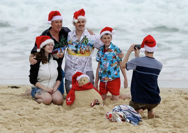 Una familia, que se ha puesto las gorras de Navidad, se toma fotos en una playa de Sidney, Australia. - Sputnik Mundo