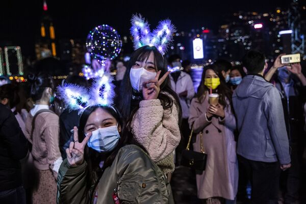 Dos mujeres posan para una foto en Victoria Harbour en Hong Kong las primeras horas del 1 de enero. Pese a las restricciones impuestas debido a la pandemia del coronavirus COVID-19 y la cancelación del 'show' de fuegos artificiales de Año Nuevo, un gran número de personas se reunió en el local para celebrar la llegada del 2021. - Sputnik Mundo