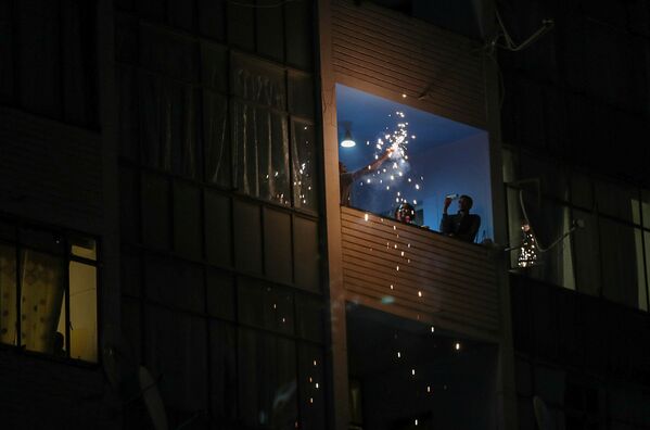Unas personas celebran la llegada del año nuevo en el balcón de su casa debido al toque de queda nocturno impuesto por las autoridades en Johannesburgo, (Sudáfrica) a causa de la pandemia del COVID-19. - Sputnik Mundo