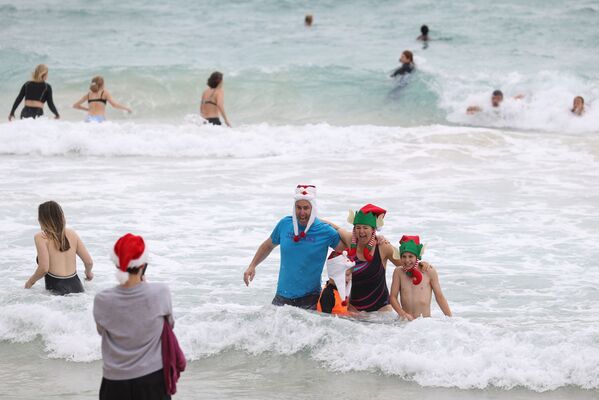 Personas con atuendos navideños posan para fotos el día de Navidad en Bondi Beach en Sídney (Australia). - Sputnik Mundo
