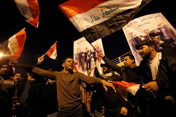 Unas personas ondean banderas en Bagdad (Irak) durante el primer aniversario de los asesinatos de Qasem Soleimani y Abu Mahdi Muhandis. - Sputnik Mundo
