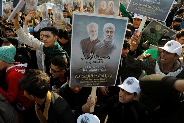 Ciudadanos iraquíes sostienen fotografías de Soleimani y Muhandis en las conmemoraciones del primer aniversario de sus asesinatos, en Bagdad (Irak). - Sputnik Mundo