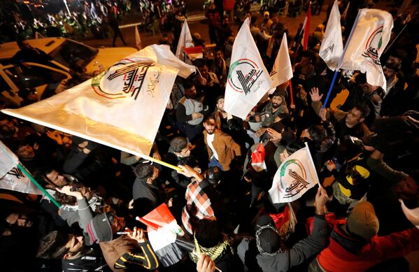 Unas personas ondean banderas en Bagdad (Irak) durante el primer aniversario de los asesinatos de Soleimani y Muhandis. - Sputnik Mundo