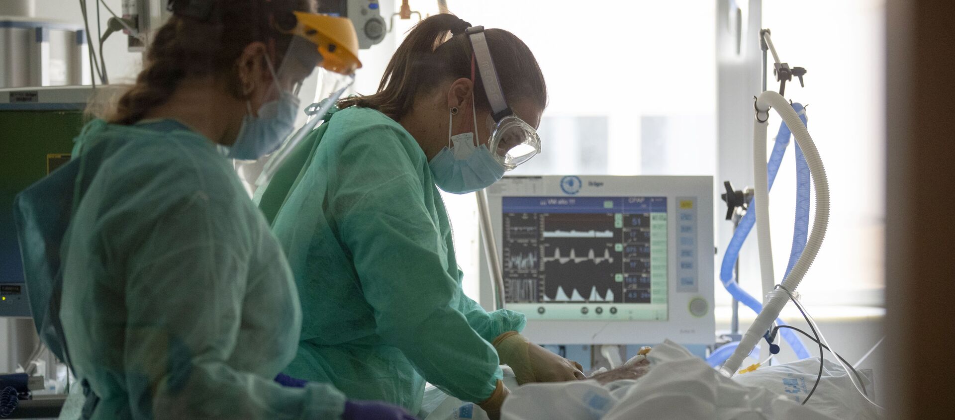 Trabajadores sanitarios asisten a un paciente con COVID-19 en una de las unidades de cuidados intensivos (UCI) del Hospital Universitario de Torrejón Trabajadores sanitarios asisten a un paciente con COVID-19 en una de las unidades de cuidados intensivos (UCI) del Hospital Universitario de Torrejón - Sputnik Mundo, 1920, 18.01.2021