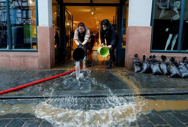 Las empleadas de una tienda de ropa vacían cubos de agua mientras limpian el establecimiento inundado después de fuertes lluvias en la ciudad de Fráncfort (Alemania), el 30 de enero. - Sputnik Mundo