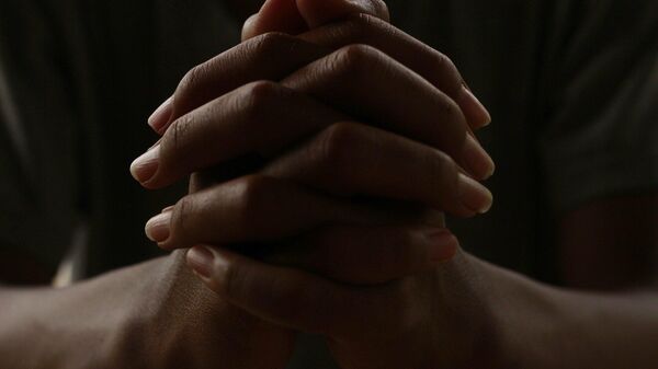 Una persona rezando con las manos entrelazadas - Sputnik Mundo