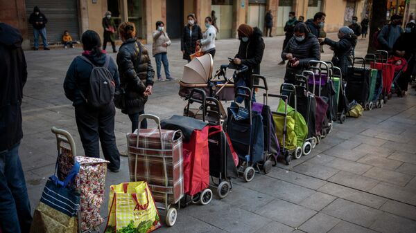 Carritos de compras alineados junto a sus dueños, esperando su turno para recibir un paquete semanal de alimentos y suministros donados, afuera de una iglesia en Barcelona, ​​España - Sputnik Mundo