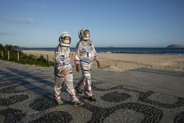 Una pareja vestida de astronautas para protegerse del coronavirus en la playa de Ipanema, en Río de Janeiro. - Sputnik Mundo