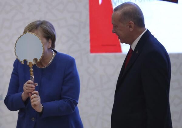 La canciller alemana, Angela Merkel, bromea frente a un espejo que le regaló el presidente turco, Recep Tayyip Erdogan, en Estambul, 2020.  - Sputnik Mundo