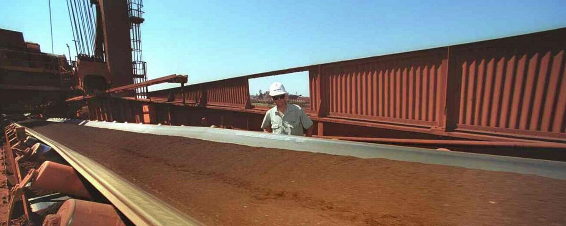 Un trabajador observa una cinta transportadora mientras se extrae mineral de hierro de la Zona Minera C en Pilbara (Australia Occidental) - Sputnik Mundo, 1920, 06.04.2021
