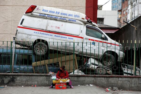 Un vendedor sentado junto a una ambulancia abandonada cerca de un hospital durante la segunda ola de coronavirus en Katmandú (Nepal), el 4 de mayo de 2021. - Sputnik Mundo
