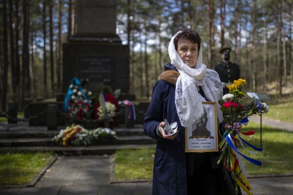 Una mujer sostiene un retrato de un familiar que participó en la Segunda Guerra Mundial durante una ceremonia con motivo del 76 aniversario del fin de la Segunda Guerra Mundial en el memorial Paneriai.  - Sputnik Mundo