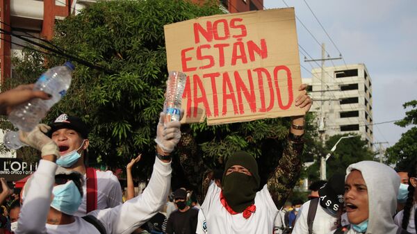 Un manifestante sostiene una pancarta que dice 'nos están matando' frente al estadio Romelio Martínez en Barranquilla. 13 de mayo de 2021 - Sputnik Mundo