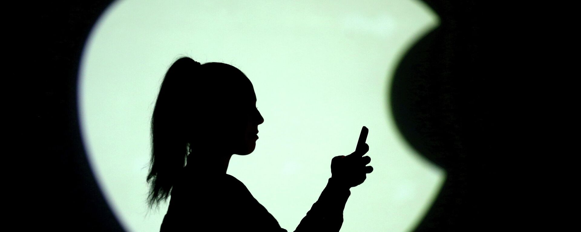 Una persona con un teléfono en el fondo del logo de Apple - Sputnik Mundo, 1920, 19.05.2021