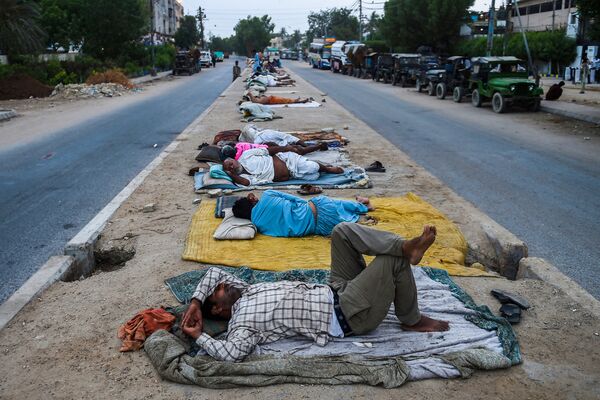 Unos trabajadores duermen en un divisor de carreteras en la ciudad portuaria de Karachi (Pakistán). - Sputnik Mundo