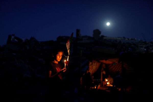 Un  palestino con una vela sobre las ruinas de su casa. - Sputnik Mundo