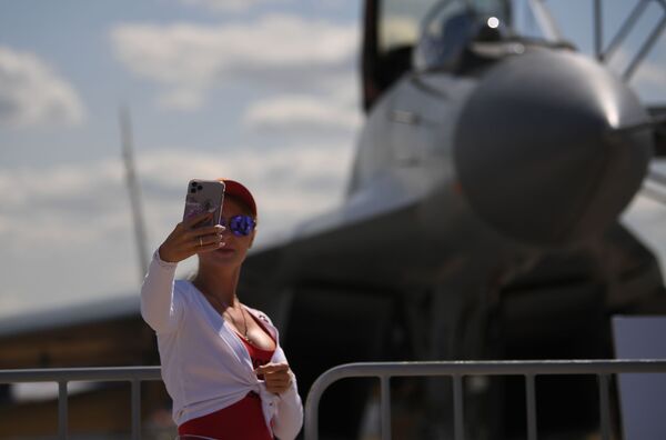 Una joven se toma una foto al lado de un MiG-35.  - Sputnik Mundo