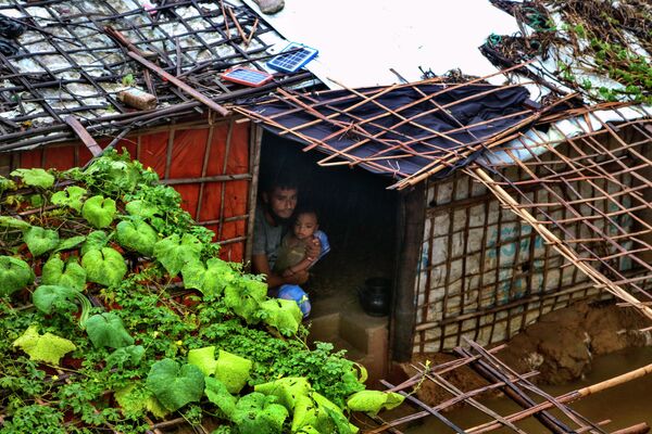 Un refugiado rohinyá y su hijo miran hacia afuera desde el interior de su refugio inundado tras las fuertes lluvias que azotaron el campo de refugiados de Kutupalong (Bangladés). Un refugiado rohinyá y su hijo miran hacia afuera desde el interior de su refugio inundado tras las fuertes lluvias que azotaron el campo de refugiados de Kutupalong (Bangladés). - Sputnik Mundo