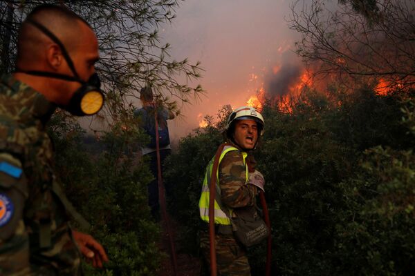 Unos bomberos voluntarios intentan controlar el fuego a las afueras de Atenas. - Sputnik Mundo