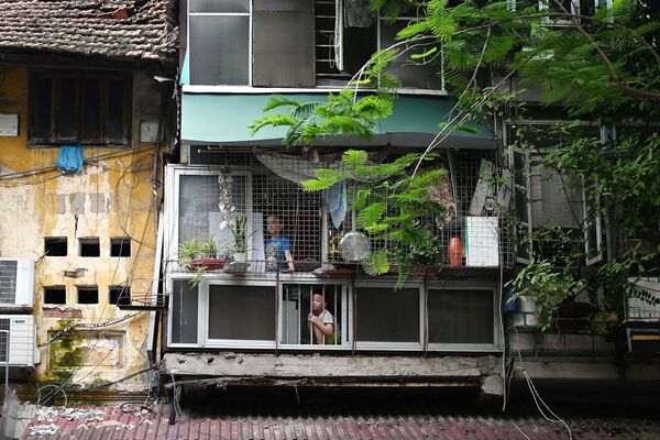 Unos niños miran las calles vacías desde el interior de su casa en Hanoi (Vietnam) el 11 de agosto, en medio de un nuevo lockdown de dos semanas impuesto por el Gobierno para detener la propagación del COVID-19 en el país. - Sputnik Mundo