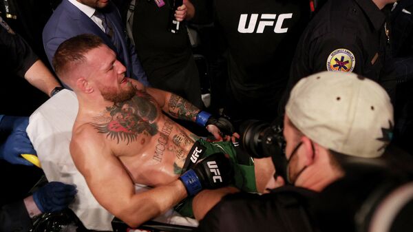 Conor McGregor, luchador de artes marciales mixtas, es cargado en una camilla tras romper la pierna en una lucha contra Dustin Poirier  - Sputnik Mundo