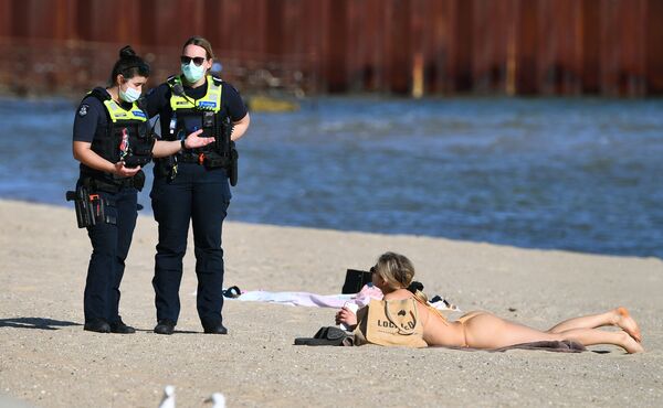Agentes de Policía hablan con una mujer que disfruta del clima primaveral inusualmente cálido en la playa de St. Kilda en Melbourne, el 2 de septiembre de 2021, mientras la ciudad permanece cerrada debido a la propagación de la variante delta del coronavirus. - Sputnik Mundo
