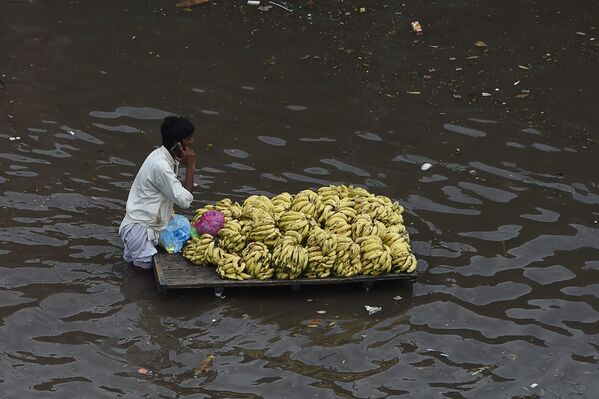 Un vendedor de fruta transporta su mercadería en una calle inundada por las fuertes lluvias en Lahore, Pakistán. - Sputnik Mundo