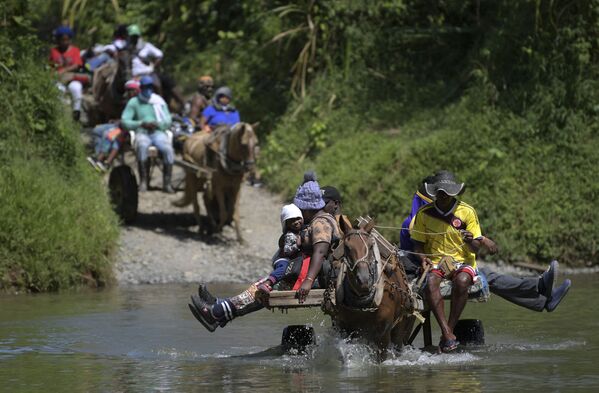 Migrantes procedentes de Haití cruzan un río en su camino hacia la frontera colombo-panameña en Akandi. - Sputnik Mundo