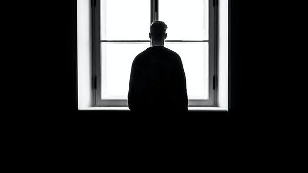 Una persona delante de una ventana en la oscuridad - Sputnik Mundo