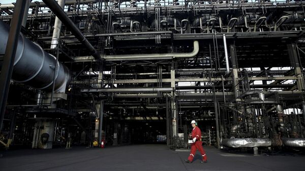 Un trabajador de un campo petrolero camina junto a los oleoductos en un complejo industrial de PDVSA  - Sputnik Mundo