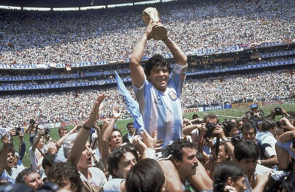 Diego Maradona sostiene el trofeo de la Copa Mundial de Fútbol de 1986, en México, tras la victoria de Argentina sobre la selección de Alemania Federal. - Sputnik Mundo